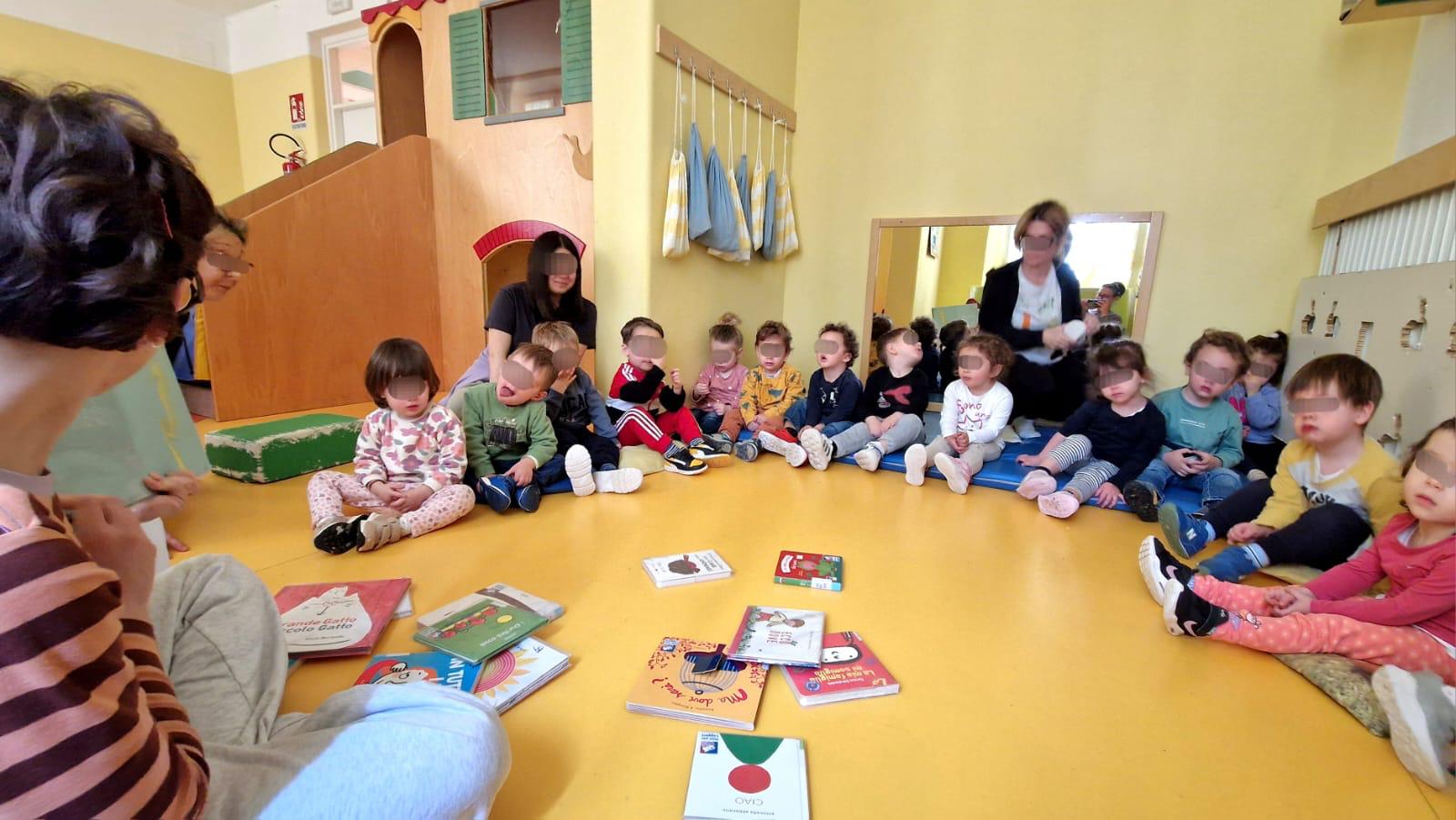 Bambini seduti in cerchio durante lettura ad alta voce